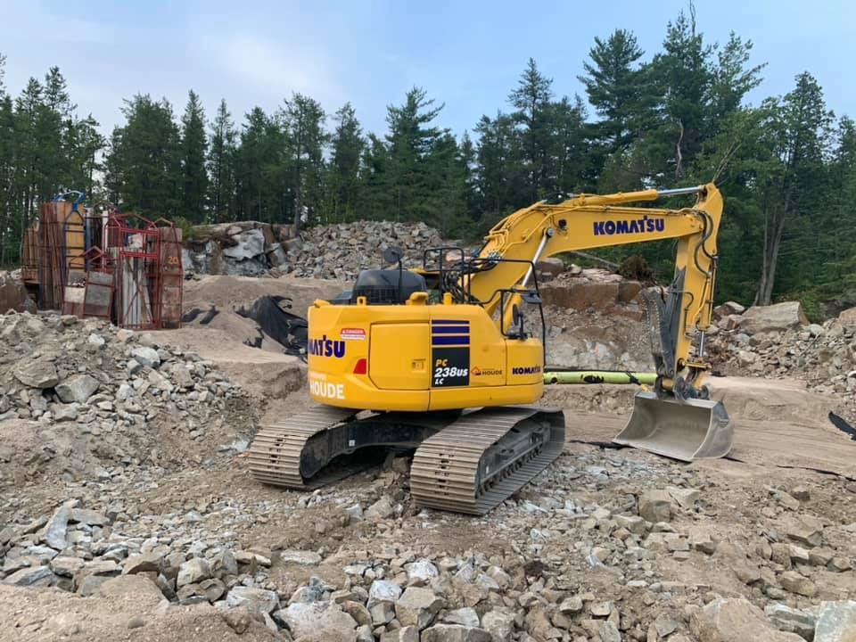 Une excavatrice jaune est assise sur un tas de rochers.