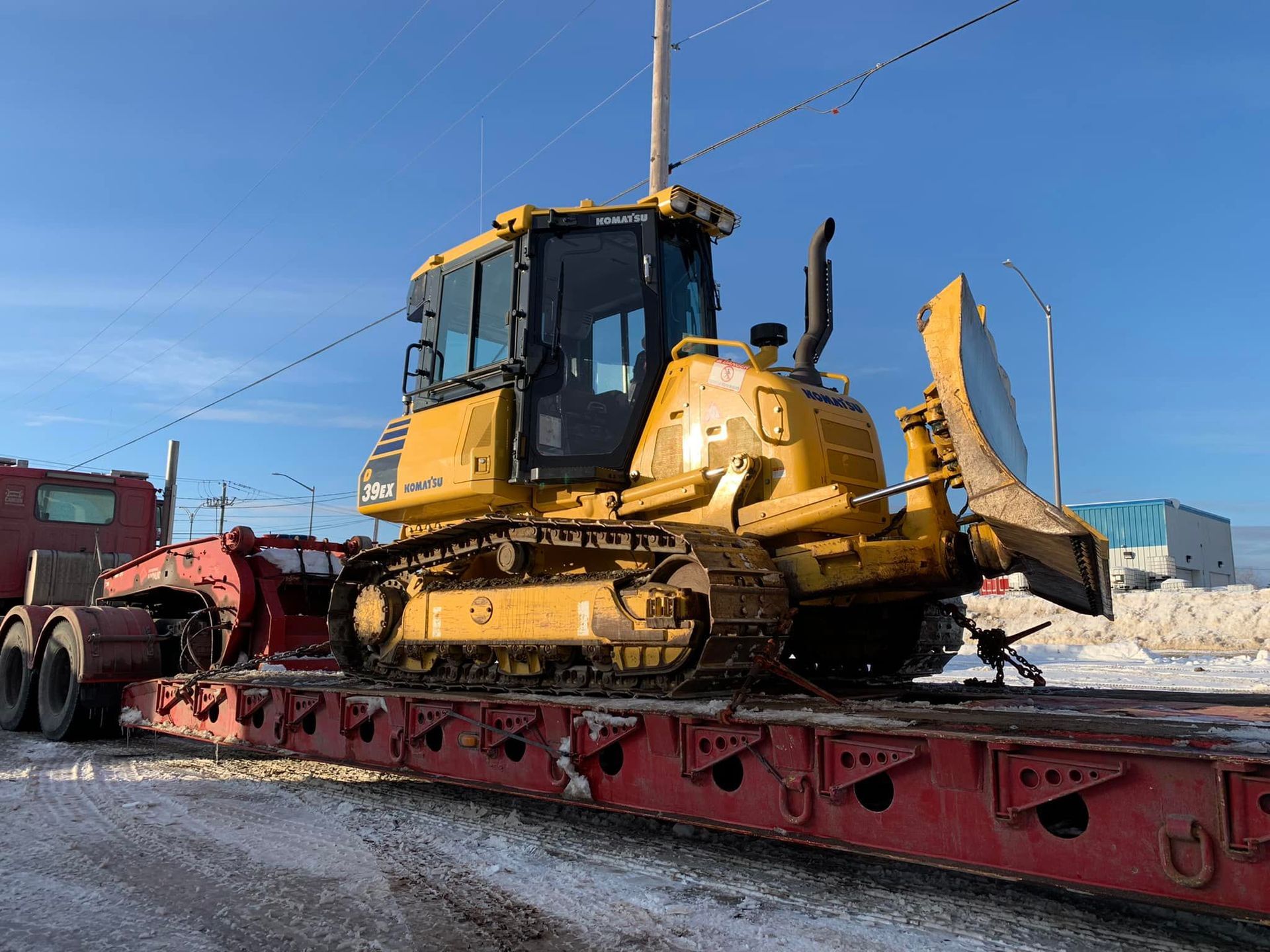 Un bulldozer jaune est assis sur une remorque rouge.