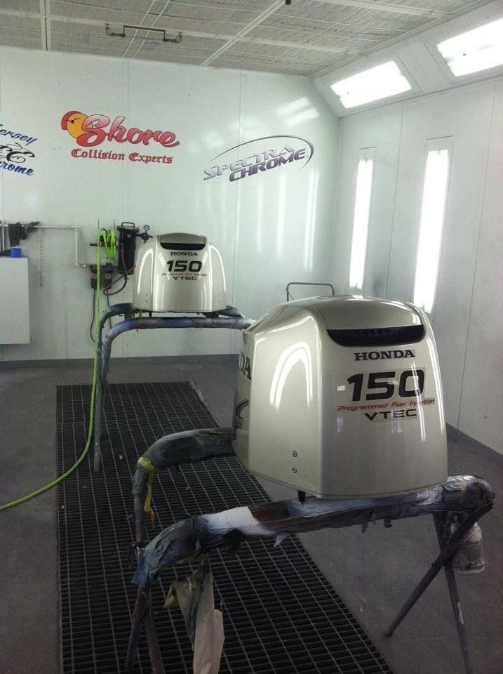 Two honda outboard motors are sitting in a paint booth.