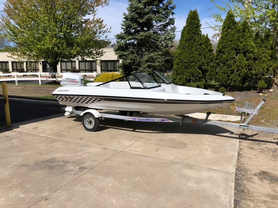 A white boat is parked on a trailer in a parking lot.