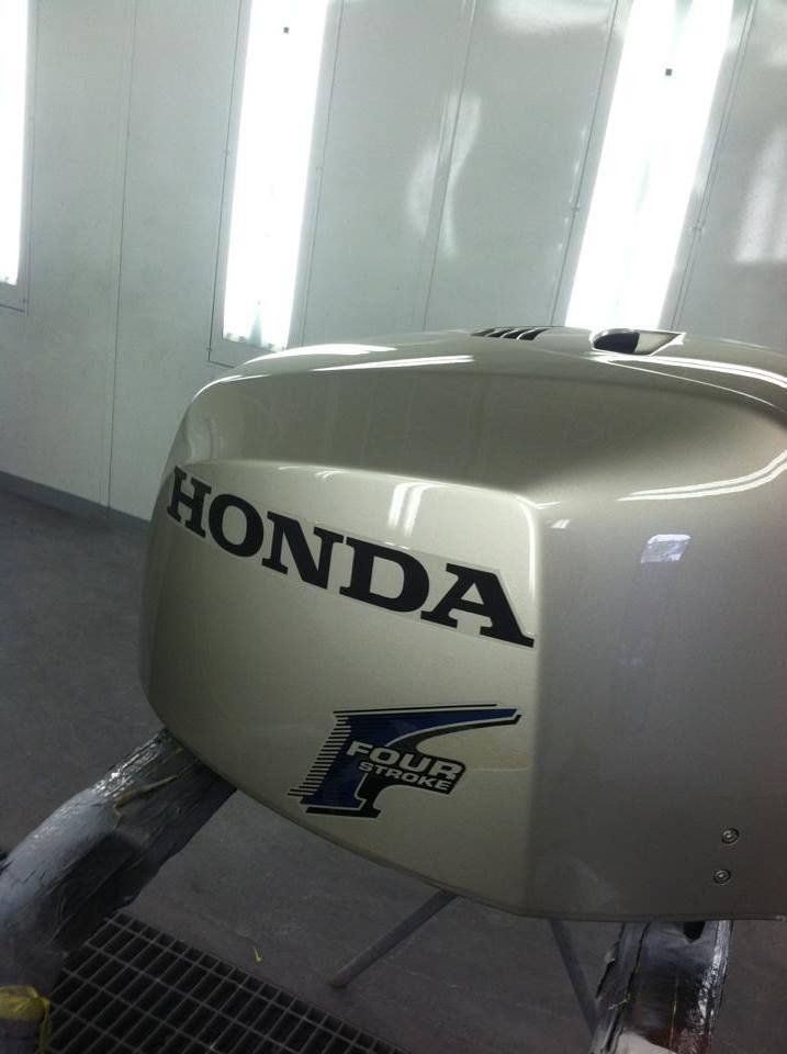 A honda four stroke outboard motor is being painted