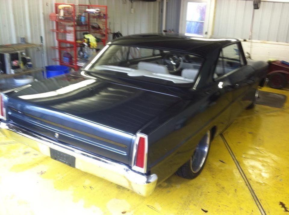 A black car is parked on a yellow floor in a garage