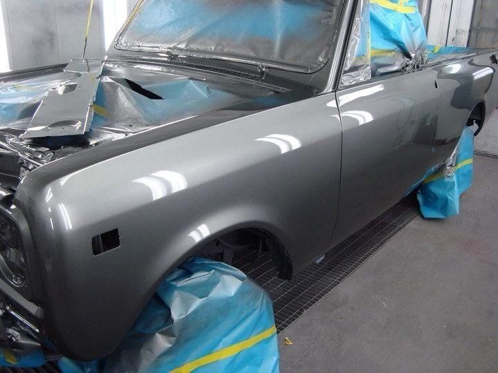 A gray car is being painted in a garage.