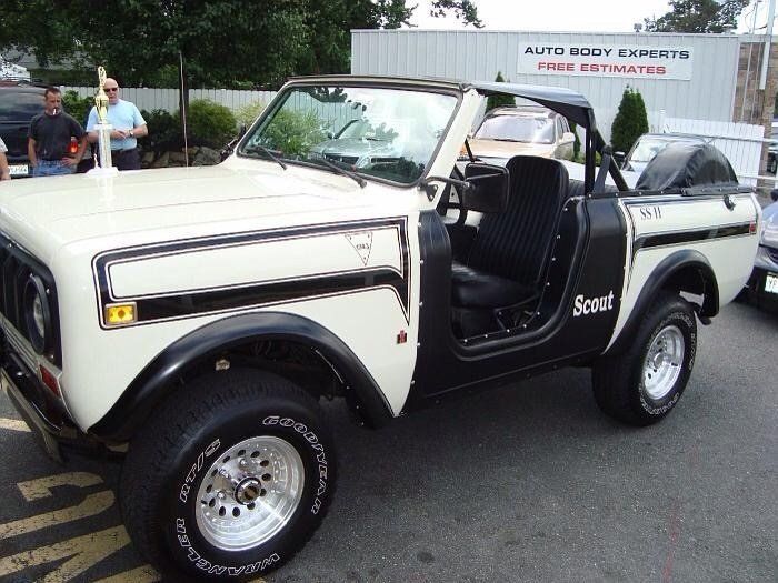 A white scout truck is parked in a parking lot