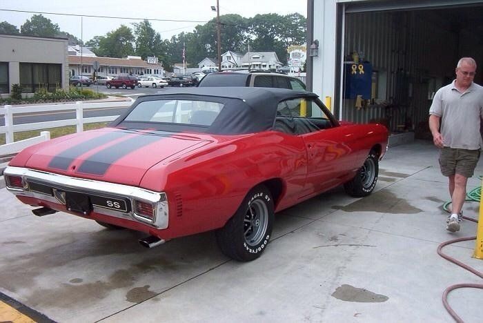 A red car with black stripes is parked in a garage