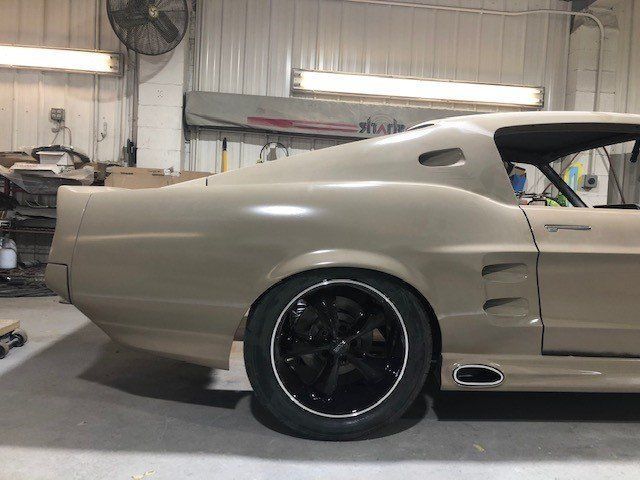 A tan car with black wheels is parked in a garage