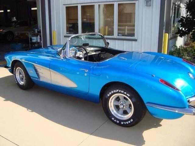 A blue sports car with goodyear tires is parked in front of a garage