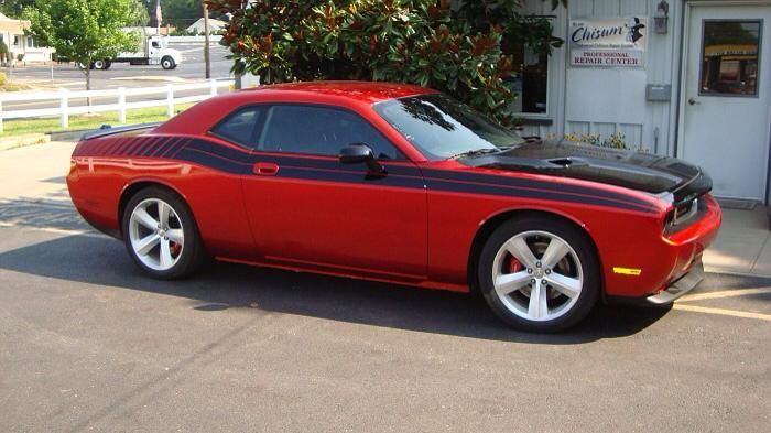 A red dodge challenger is parked in front of a building