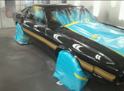 A black car with yellow stripes is covered in blue plastic