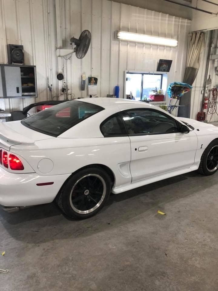 A white mustang is parked in a garage.