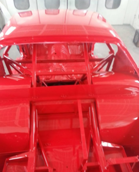A red race car is being painted in a garage