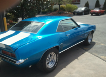 A blue car with white stripes is parked in a parking lot