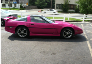 A pink sports car is parked in a parking lot