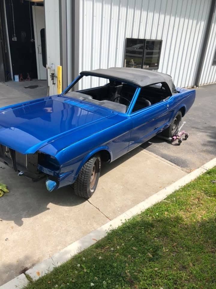 A blue car is parked on the side of the road in front of a building.