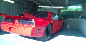 A red sports car is parked in a garage.