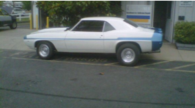 A white and blue car is parked in a parking lot