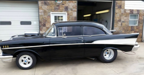 A black and white car is parked in front of a garage door.