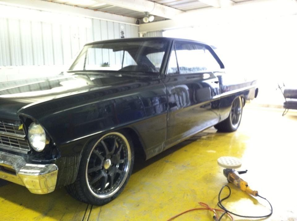 A black car is parked in a garage next to a polisher