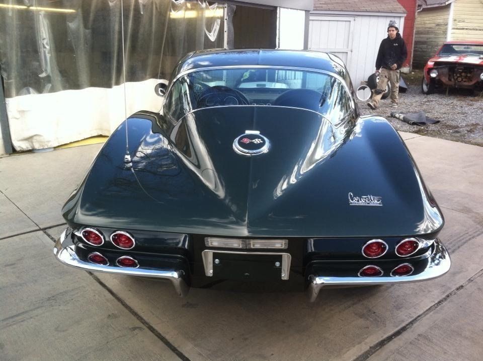 A black corvette is parked in front of a garage