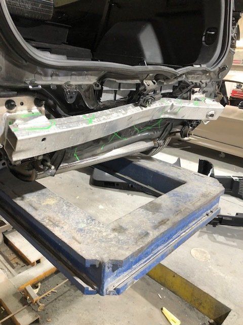 A car is being repaired on a lift in a garage.