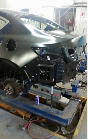 A car is sitting on a lift in a garage.