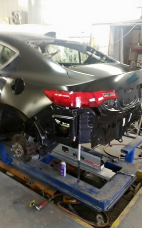 A car is sitting on a lift in a garage.
