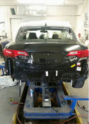 A black car is sitting on a lift in a garage