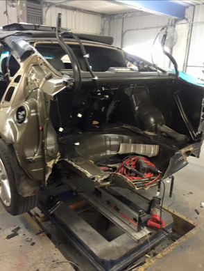 A damaged car is sitting on a lift in a garage
