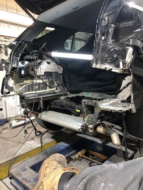 A car is being dismantled in a garage with the hood up