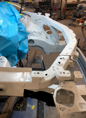A white car frame is being built in a garage