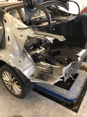 A car is being dismantled in a garage.