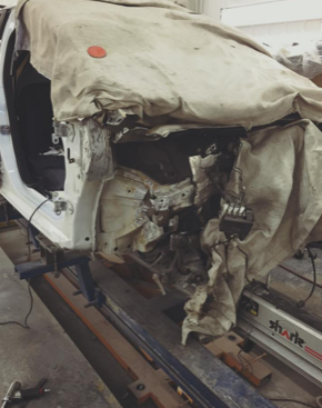 A damaged car is sitting on a hurle machine
