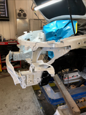 A car is being built in a garage with the hood open