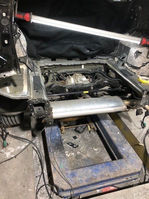A car is being worked on in a garage with the hood open.