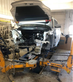 A car is being worked on in a garage with the hood open