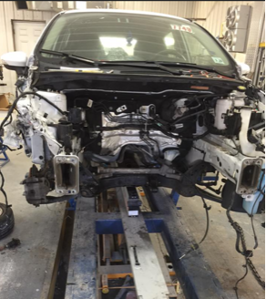 A white car is being dismantled in a garage
