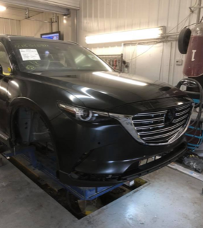 A black mazda cx 9 is sitting on a lift in a garage