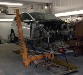 A white car is being worked on in a garage