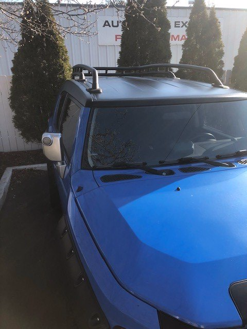 A blue jeep is parked in front of a building that says auto express