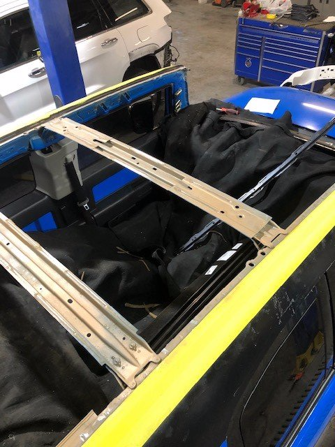 The roof of a car is being removed in a garage.