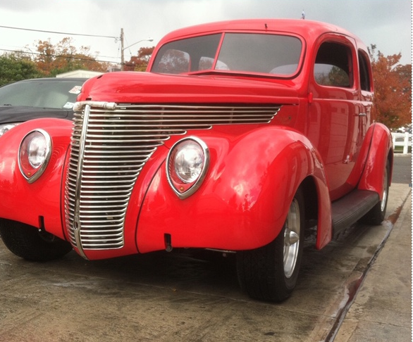 A red car is parked on the side of the road