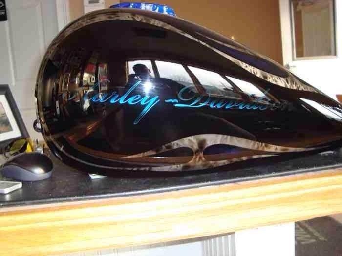A harley davidson gas tank is sitting on a wooden table
