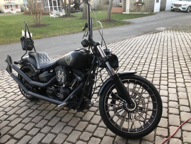 A black motorcycle is parked on a brick driveway.