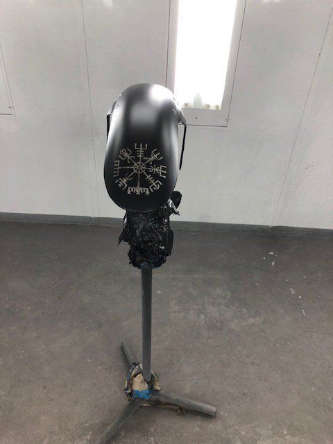 A black helmet is sitting on a stand in a room.