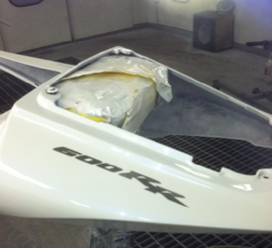 A white 500 rr motorcycle is being painted in a garage