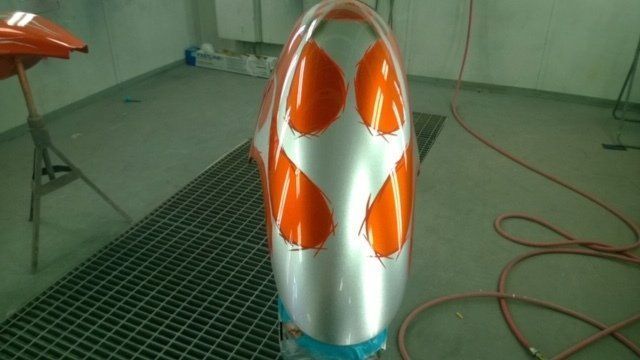 A silver and orange object is sitting on a metal grate in a room.