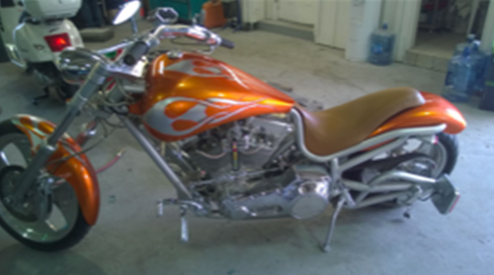 An orange motorcycle is parked in a garage