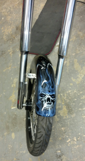A motorcycle with a skull painted on the front fender