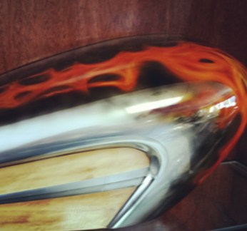 A close up of a motorcycle tank with flames painted on it