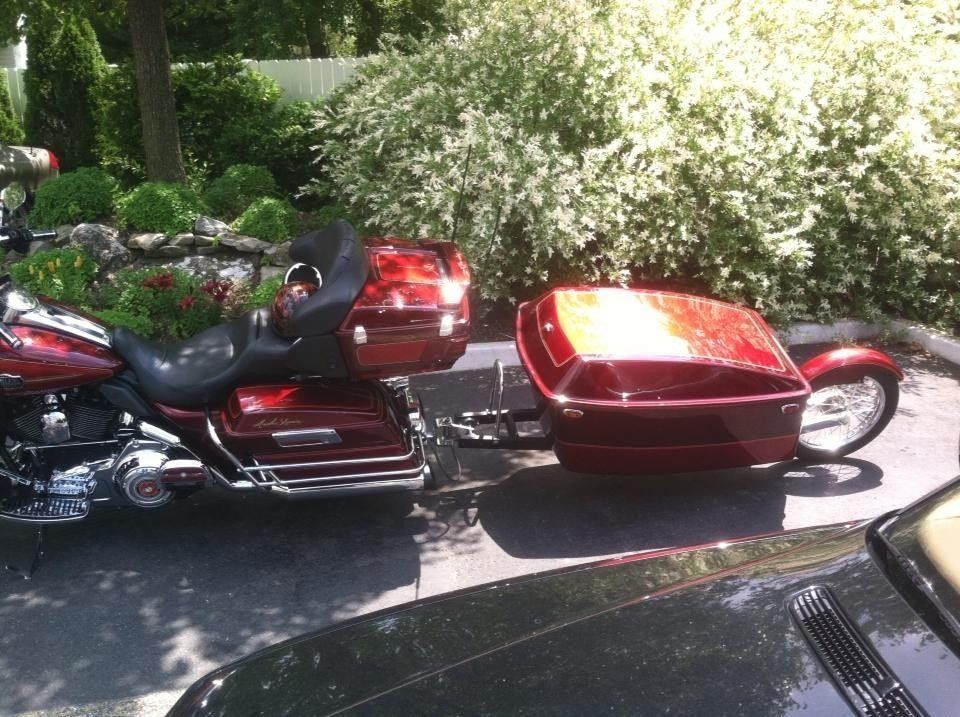 A red motorcycle is parked next to a black car